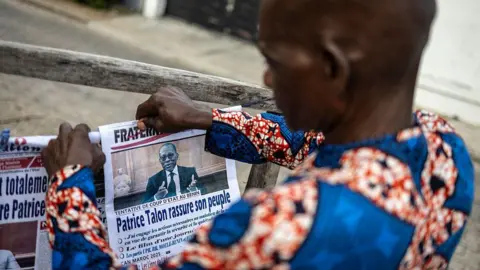 AFP via Getty Images Um vendedor exibe seu jornal no Benin um dia após a tentativa de golpe. 