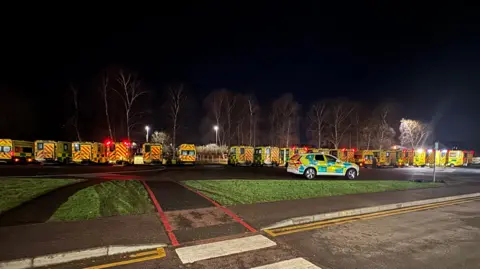 Dozens of ambulances lined up outside Gloucestershire Royal Hospital at night