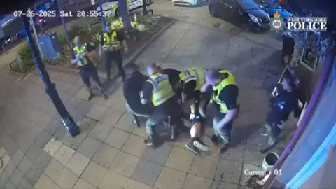 Police pinning murderer Michael Doherty to the ground with another 3 looking over on a town street.