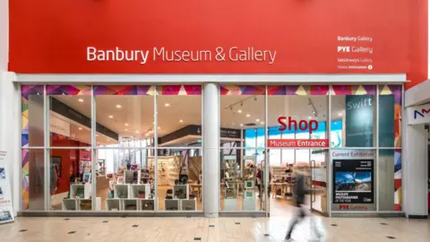 The shop entrance to the museum, which has floor to ceiling windows revealing objects within.