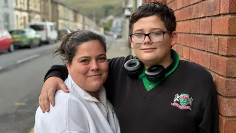 Sam and her son Owen looking at the camera. Owen has his hand around his mothers shoulder