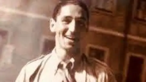 An old photo of Fredy Hirsch. He smiles at the camera. He has short dark hair and wears a shirt and tie.