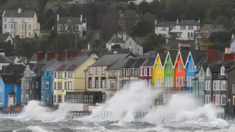 Pacemaker A row of colourful terraced houses on the coastline are sprayed by waves which are crashing onto the streets.