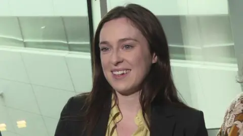 RTÉ Tori Towey smiling wearing a black blazer and yellow blouse