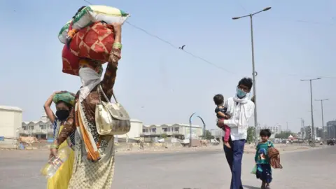 Getty Images Migrants with children walking towards Uttar Pradesh seen at the Ghazipur Delhi-UP border on May 14, 2020 in New Delhi, India