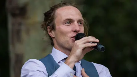 Getty Images A photo of Paul Powlesland speaking into a microphone 