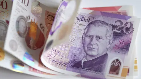 A picture of notes on a table. There is a £20, £10 and £50 note.