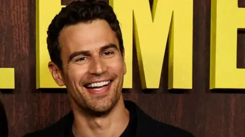 Reuters Theo James during a premiere, smiling and looking off camera