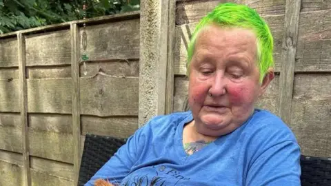 The victim of a crash, wearing a blue T-shirt and with green hair
