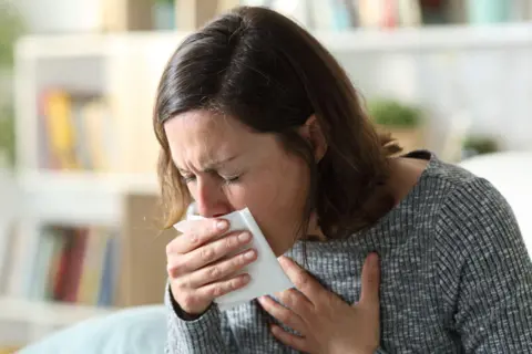 Getty Images A women coughing heavily into a tissue