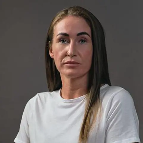 BBC Scotland Shannon, who has long, dark hair, is wearing a white T-shirt. 