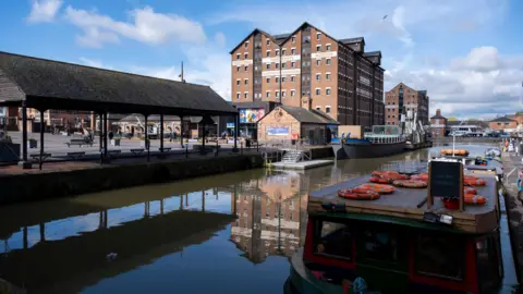 Getty Images Gloucester Docks. Buildings and a boat in the water can be seen. 