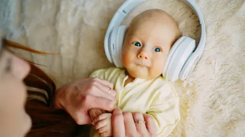 A baby is lying down with headphones on. 