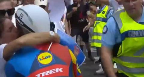 Cyclist Julien Bernard kissing his wife who has come onto the road, he is pictured from behind and other spectators are crowding the road