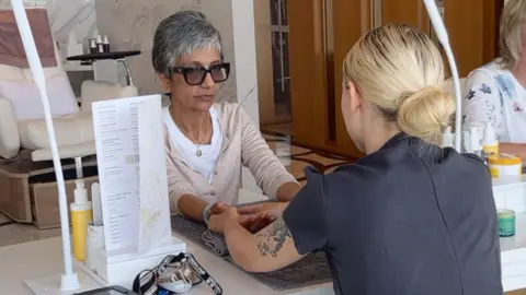 BBC Sindy Sidhu sits in a spa with her hands on a table while being massaged by a therapist