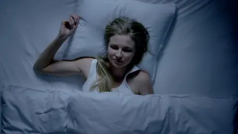 A woman with her eyes closed in bed