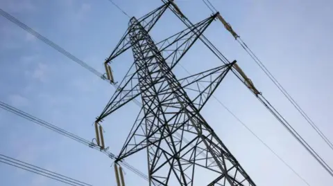 A black power pylon with a blue sky in the background.