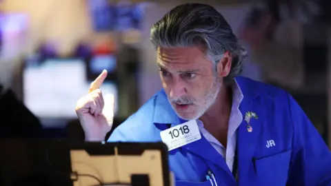 Getty Images US stock trader with grey hair and beard, wearing a blue trading jacket with number badge