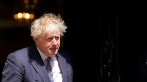 PA Media Boris Johnson wearing a dark suit and patterned tie, stepping out of the black door of 10 Downing Street 