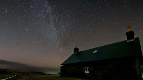 Steven Gray/Cosmos Planetarium A house on Rum at night with stars in the sky above it