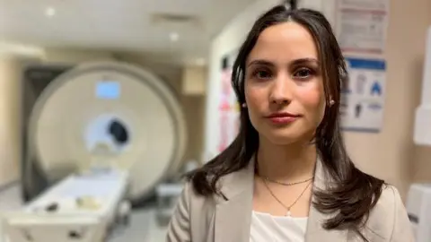 Researcher Izabelle Lovgren standing in front of an MRI scanner