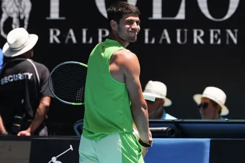 Carlos Alcaraz adjust a wearable device at the Australia Open