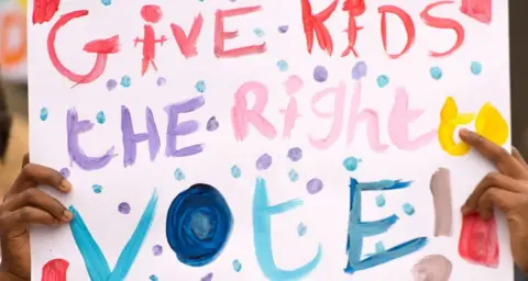 Getty Images A colourful sign saying: 'Give kids the right to vote!'