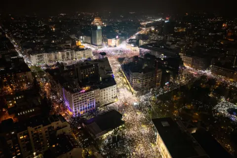 Getty Images Photograph shows protesters holding up their mobile phones to light up the night sky in memory of those who died in the Novi Sad disaster