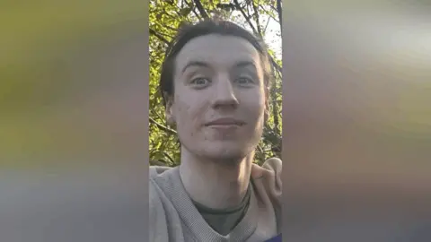 A close-up image of Finbar Sullivan's face. He is a young, slender man with dark hair. 