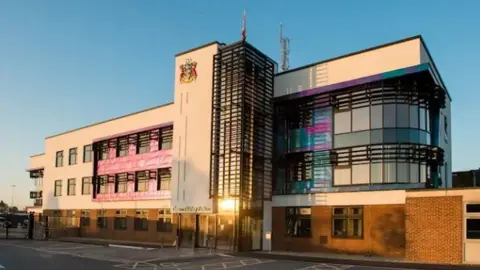 TVP Thames Valley Police headquarters in Kidlington, a three-storey building with TVP's logo at the top of a column that stretches out from the centre of it 