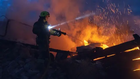 Reuters A firefighter sprays water from a hose at flames in Sumy.