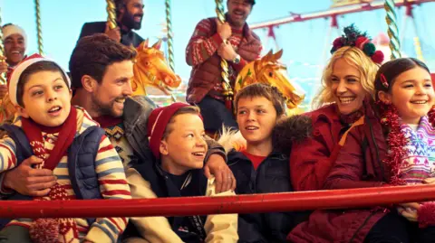 Christmas Karma Leo Suter and Pixie Lott with a group of children in Christmas Karma