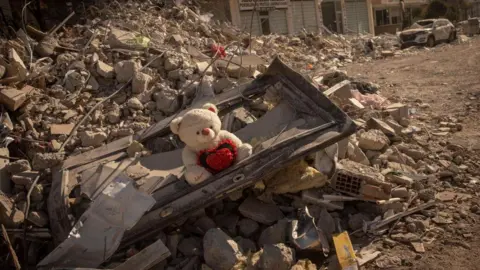 Getty Images A teddy bear is seen amid rubble from a destroyed building on February 13, 2023 in Nurdagi, Turkey