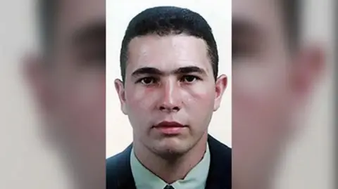 Metropolitan Police/PA Wire Passport-style photo of Jean Charles de Menezes. He has short dark hair and is wearing a green shirt and black jacket.