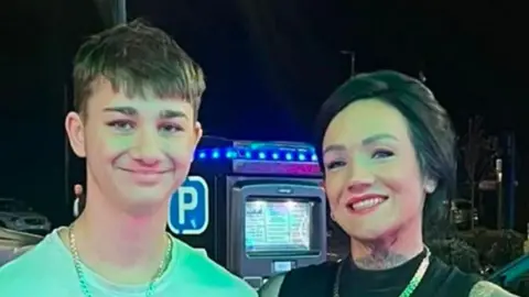 Supplied A head and shoulders image of Rocco and his mum Jade. Rocco is wearing a light coloured T-shirt with a chain around his neck. Jade is wearing a black top with a chain around her neck. They are both smiling and looking into the camera.