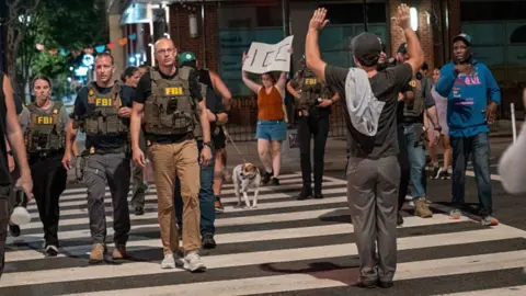 FBI agents are followed by protesters in the U-street neighbourhood on August 13, 2025 in Washington, DC