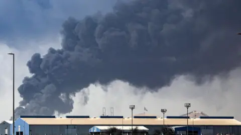 Thick black smoke billows into the air above the Jebel Ali port. 