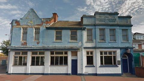 A derelict pub building with blue and white frontage