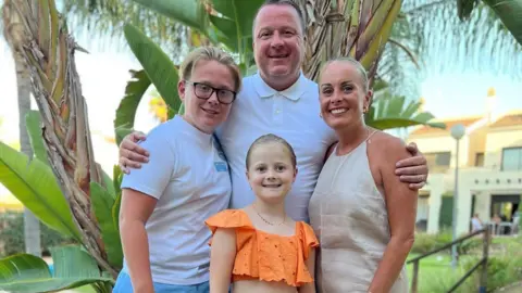 Supplied Family photo of two children and parents in front of a palm tree