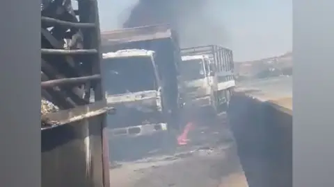 Damaged and burning vehicle on the road across Jebel Auryadam Bridge