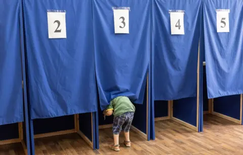 ELENA COVALENCO/AFP A child takes a peek inside a booth at a polling station in Moldova