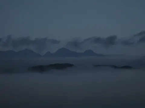 János Domján Mountains with clouds in the foreground and background.