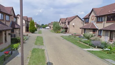 A residential street with modern two‑storey houses made of light brick. 