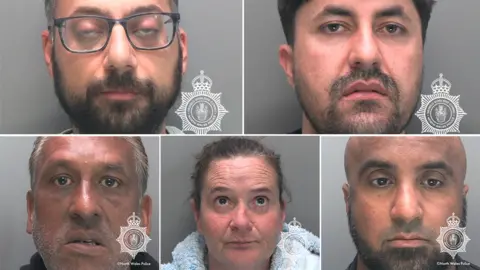 A composite image of five police mugshots. Top right is a man with a dark beard and glasses. Top left is a man with a stubbly beard and moustache. Bottom left is a man with grey stubble. Middle bottom is a woman with scrapped back dark hair, and bottom right is a bald man with a black beard. They are all head shots and they are all looking at the camera.