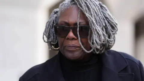 Janice Nix leaving the Old Bailey, wearing a black coat and sunglasses