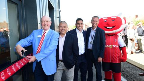 Lincoln City staff with the ribbon at the new community hub, alongside a mascot
