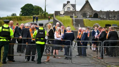 A group of Orange Order members and DUP's Carla Lockhart being blocked by police from walking down a road. 
