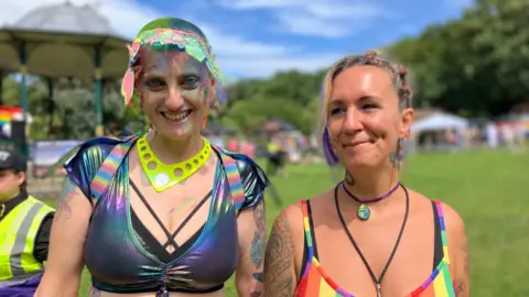 Two women both wearing multi-coloured tops, smiling at the camera