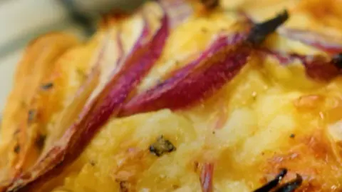 A close-up image of a cheddar and red onion tartlet.