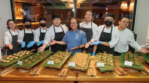 Serangga untuk Memberi Makan Dunia Nicholas Low (ketiga dari kanan) dan Joseph Yoon (keempat dari kanan) memimpin tim yang menyiapkan prasmanan jangkrik untuk para peserta Serangga untuk Memberi Makan Dunia